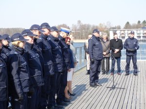 Komendant Miejski Policji w Olsztynie przemawia do mikrofonu w towarzystwie kierownictwa olsztyńskiej jednostki policji w skład której wchodzą naczelnicy poszczególnych wydziałów.