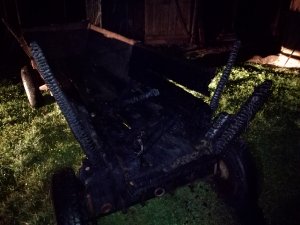Zdjęcie przedstawia zniszczony wyniku pożaru drewniany wóz.