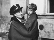 Zdjęcie przedstawia policjantkę, która trzyma na rękach dziecko.
