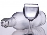 Zdjęcie przedstawia pustą butelkę po alkoholu i kieliszek
