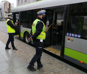 Zdjęcie przedstawia policjantów przed autobusem.
