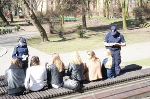 Zdjęcie przedstawia policjantów legitymujących grupę młodych osób.