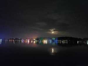 Zdjęcie przedstawia jezioro oraz w tle światła z plaży.