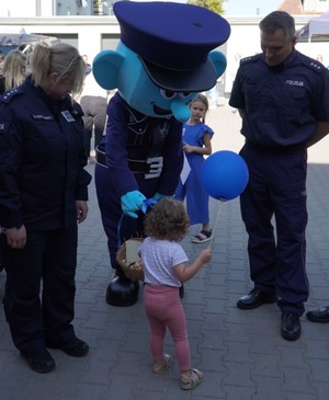 Zdjęcie przedstawia umundurowanych policjantów wraz z maskotką Benusia oraz małe dziecko.