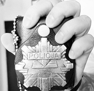 Zdjęcie przedstawia fragment policyjnej odznaki w dłoni