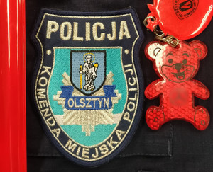 Zdjęcie przedstawia elementy odblaskowe i napis Komenda Miejska Policji w Olsztynie