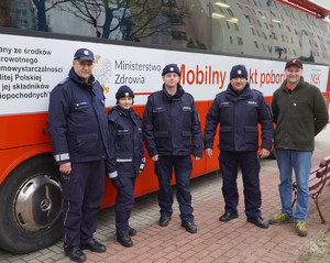 Zdjęcie przedstawia policjantów i osobę cywilną przed autobusem.