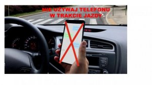 Zdjęcie przedstawia osobę, która trzyma w ręku telefon komórkowy w trakcie jazdy samochodem.