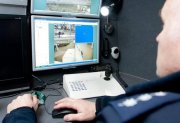 Zdjęcie przedstawia policjanta, który przegląda nagranie z monitoringu.