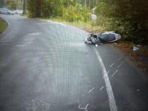 Zdjęcie przedstawia motorower leżący na jezdni.