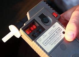 Zdjęcie przedstawia badanie policyjnym alkomatem.