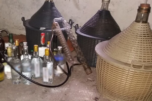Zdjęcie przedstawia zabezpieczony nielegalny alkohol oraz sprzęt do jego produkcji.