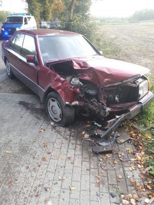 Zdjęcie przedstawia samochód, który uczestniczył w wypadku drogowy, w tle znajduje się policyjny radiowóz.