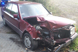 Zdjęcie przedstawia samochód osobowy, który uczestniczył w wypadku drogowym. W tle znajduje się policyjny radiowóz.