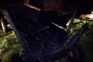 Zdjęcie przedstawia zniszczony w wyniku pożaru drewniany wóz.