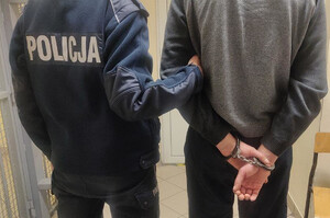 Zdjęcie przedstawia policjantkę która prowadzi zatrzymanego mężczyznę.