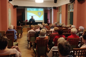 Zdjęcie przedstawia umundurowaną policjantkę, która prowadzi spotkanie z seniorami.