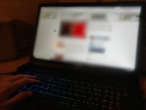 Zdjęcie przedstawia laptop i rękę mężczyzny