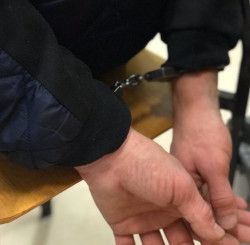 Zdjęcie przedstawia ręce w kajdankach policyjnych