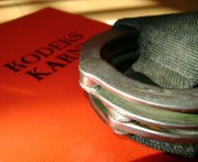 Zdjęcie przedstawia kajdanki i kodeks karny