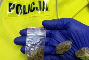 Zdjęcie przedstawia fragment  policjanta, który trzyma substancje zabronione.