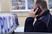 Zdjęcie przedstawia policjanta rozmawiającego przez telefon.