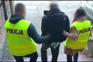 Zdjęcie przedstawia dwóch policjantów, którzy prowadzą zatrzymanego.