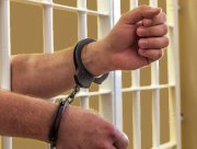 Zdjęcie przedstawia mężczyznę za kratami.