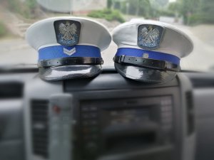 Zdjęcie przedstawia policyjne czapki ruchu drogowego w radiowozie.
