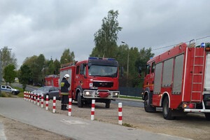 Zdjęcie przedstawia akcje ewakuacyjną w Dywitach. Na zdjęciu znajdują się dwa wozy strażackie. W tle dwa policyjne radiowozu, jedne oznakowany, drugi nieoznakowany.