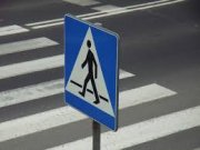Zdjęcie przedstawia fragment oznakowanego przejścia dla pieszych znakami poziomymi i pionowymi.