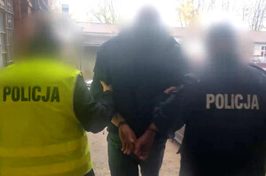 Zdjęcie przedstawia policjantów prowadzących zatrzymanego mężczyznę.