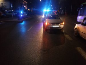 Zdjęcie przedstawia miejsce zdarzenia drogowego na ul. 1-go Maja w Olsztynie. Na zdjęciu znajdują się pojazdy, w tle policyjny radiowóz.