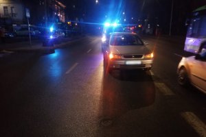 Zdjęcie przedstawia miejsce zdarzenia drogowego na ul. 1-go Maja w Olsztynie. Na zdjęciu znajdują się pojazdy, w tle policyjny radiowóz.