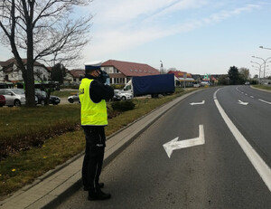 Zdjęcie przedstawia umundurowanego policjanta, który wykonuje pomiar prędkości.