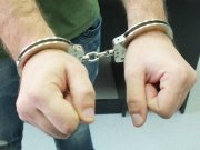 Zdjęcie przedstawia fragment mężczyzny, który ma ręce w kajdankach.