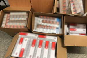 Zdjęcie przedstawia zabezpieczone nielegalne papierosy bez polskich znaków akcyzy w kartonach na podłodze.