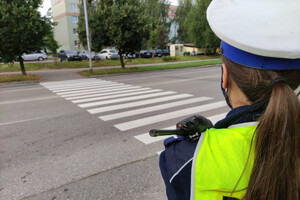 Zdjęcie przedstawia fragment policjantki, która stoi przed przejściem dla pieszych.