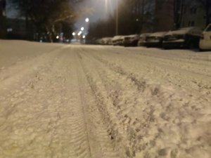 Zdjęcie przedstawia fragment zaśnieżonej ulicy.