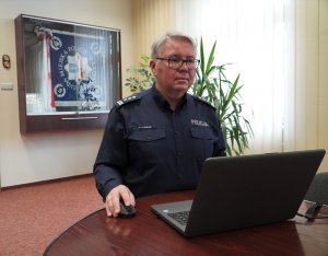 Zdjęcie przedstawia insp. Piotra Zabuskiego przed laptopem. W tle znajduje się w gablocie Sztandar KMP w Olsztynie.