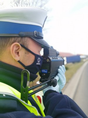 Zdjęcie przedstawia fragment policjanta kontrolującego prędkość.