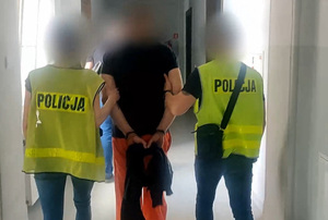 Zdjęcie przedstawia prowadzenie zatrzymanego mężczyznę.