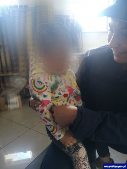 Policjanta trzyma dziecko na rękach.