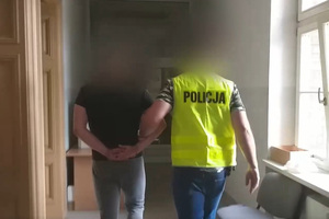 Zdjęcie przedstawia prowadzenie zatrzymanego mężczyzny.