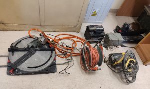 Zdjęcie przedstawia zabezpieczone przedmioty przez policjantów położone na podłodze m.in. elektronarzędzia, narzędzia oraz skrzynka energetyczna.