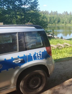 Miejsce zdarzenia nad jeziorem Gilgajno . Na zdjęciu znajduję się policyjny radiowóz oraz w tle akwen.