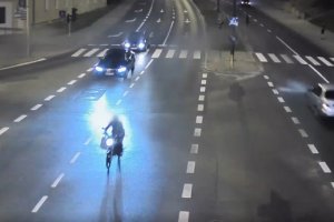 Zdjęcie przedstawia kard z filmu na którym widoczny jest motocyklista jadący ulicą i samochody jadące za nim.