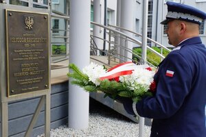 Nadinsp. Tomasz Klimek składa kwiaty pod tablicą patrona.