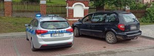 Zdjęcie przedstawia dwa zaparkowane auta - policyjny radiowóz i osobowy chrysler.