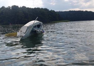Zdjęcie przedstawia przewróconą łódź na jeziorze.